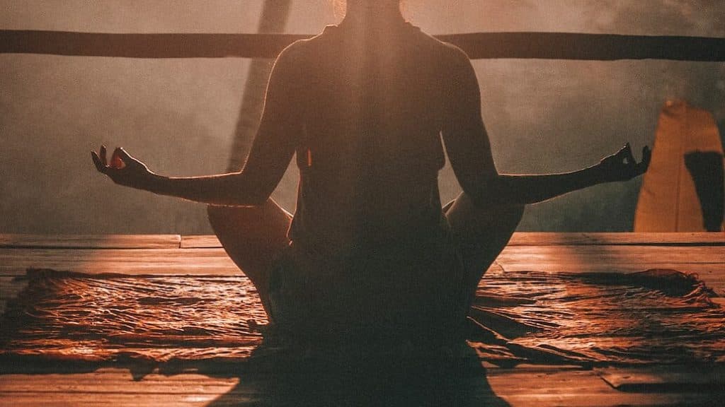 woman doing yoga meditation on brown parquet flooring